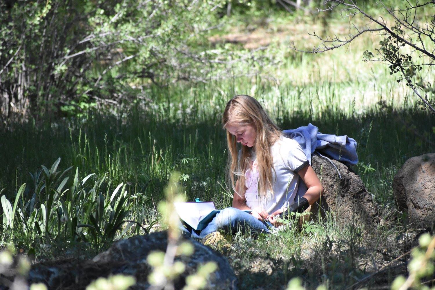 Camp youth scatter among the trees for quiet time and prayer. Photo.