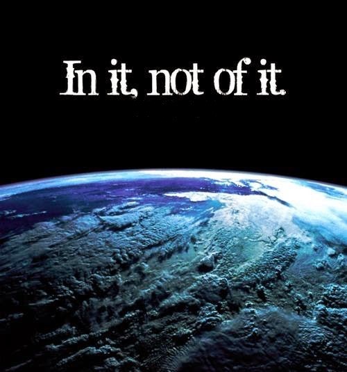 Photo of Planet Earth in shades of blue against a black sky with the words "In it, not of it" across the darkness.