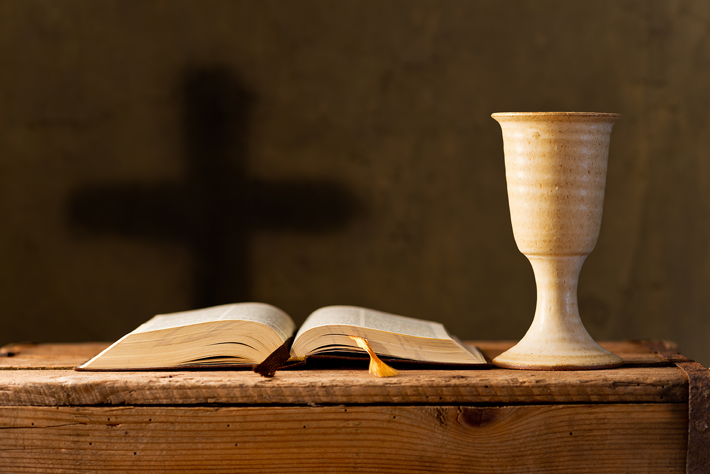 Communion cup and open bible on a rustic wooden table