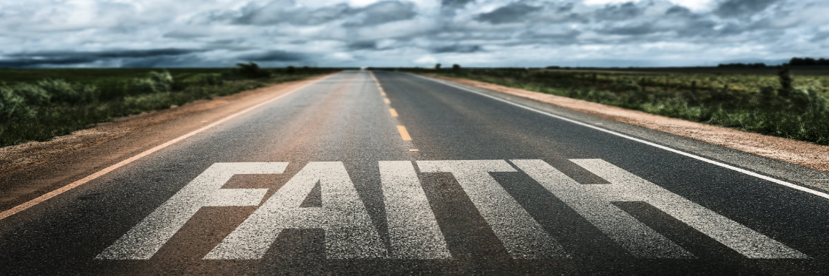 Photo of an empty highway with the word FAITH painted across the full width.