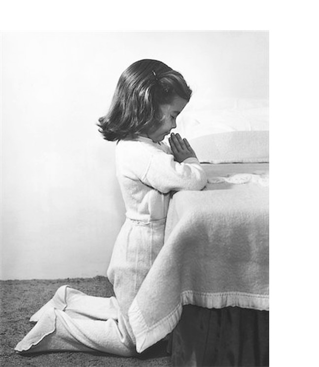Young girl kneeling, praying beside her bed